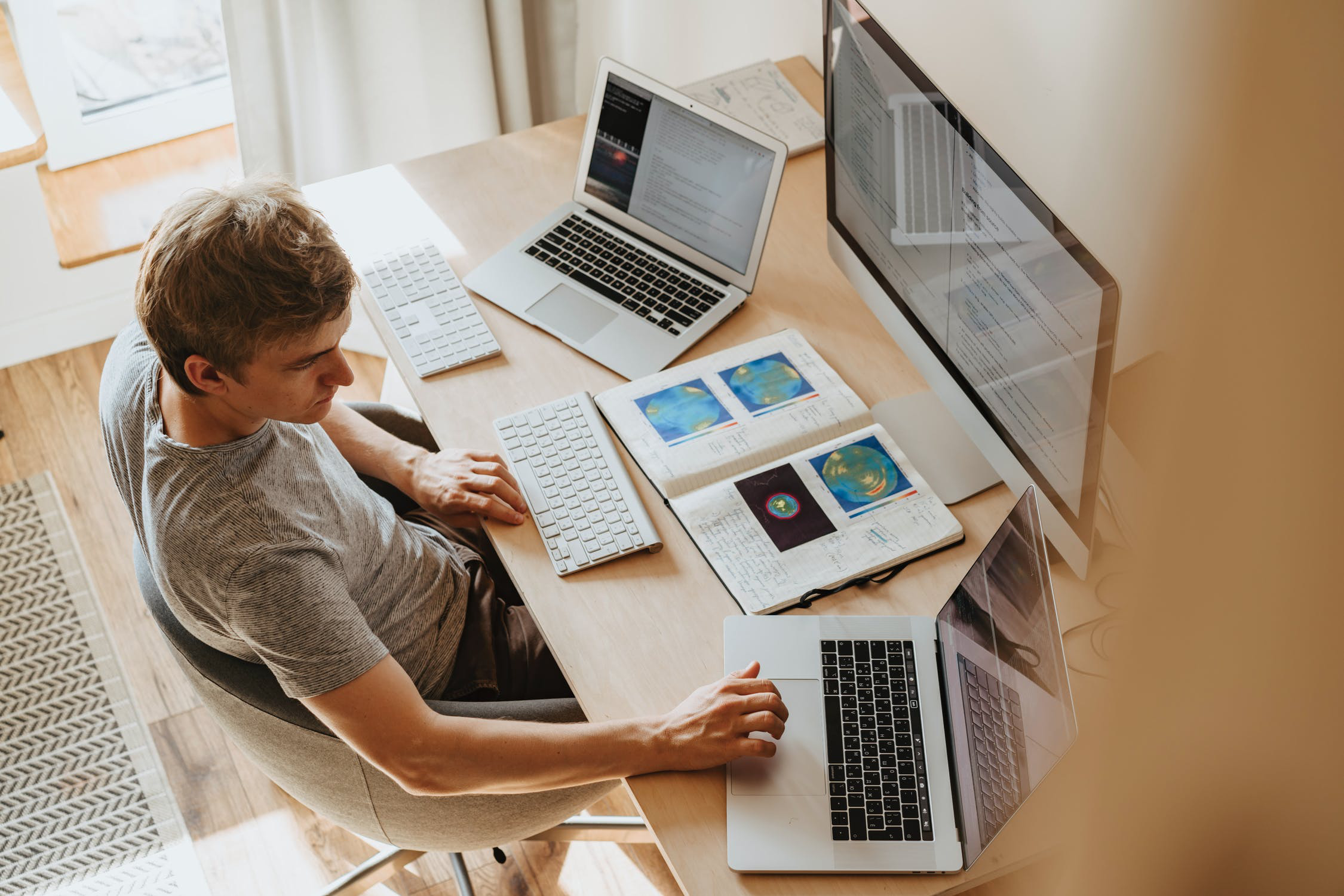 Man looking at three computer screens