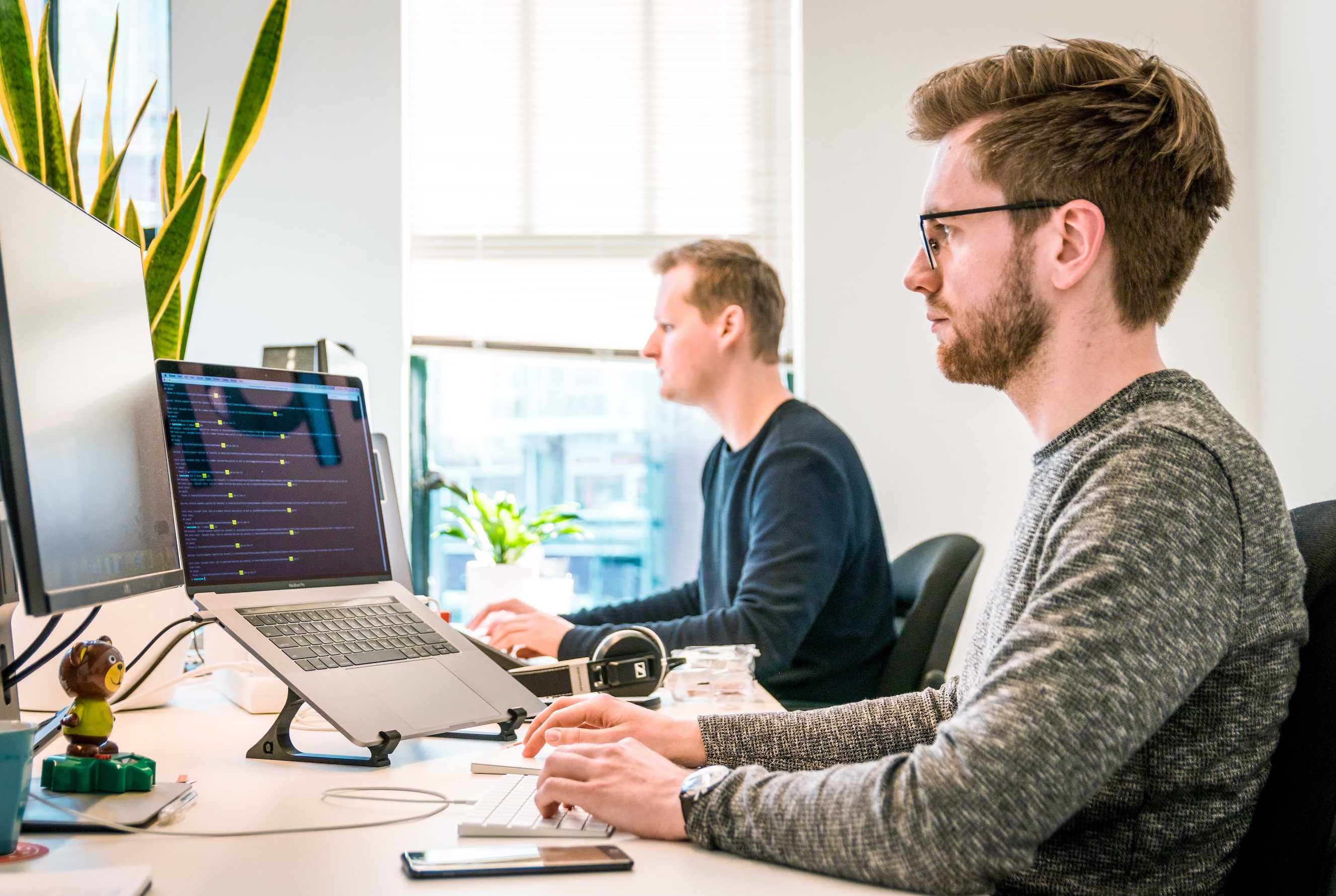 Two man looking at computers in an office