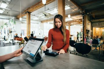 Person smilling and paying at the counter of a cafe