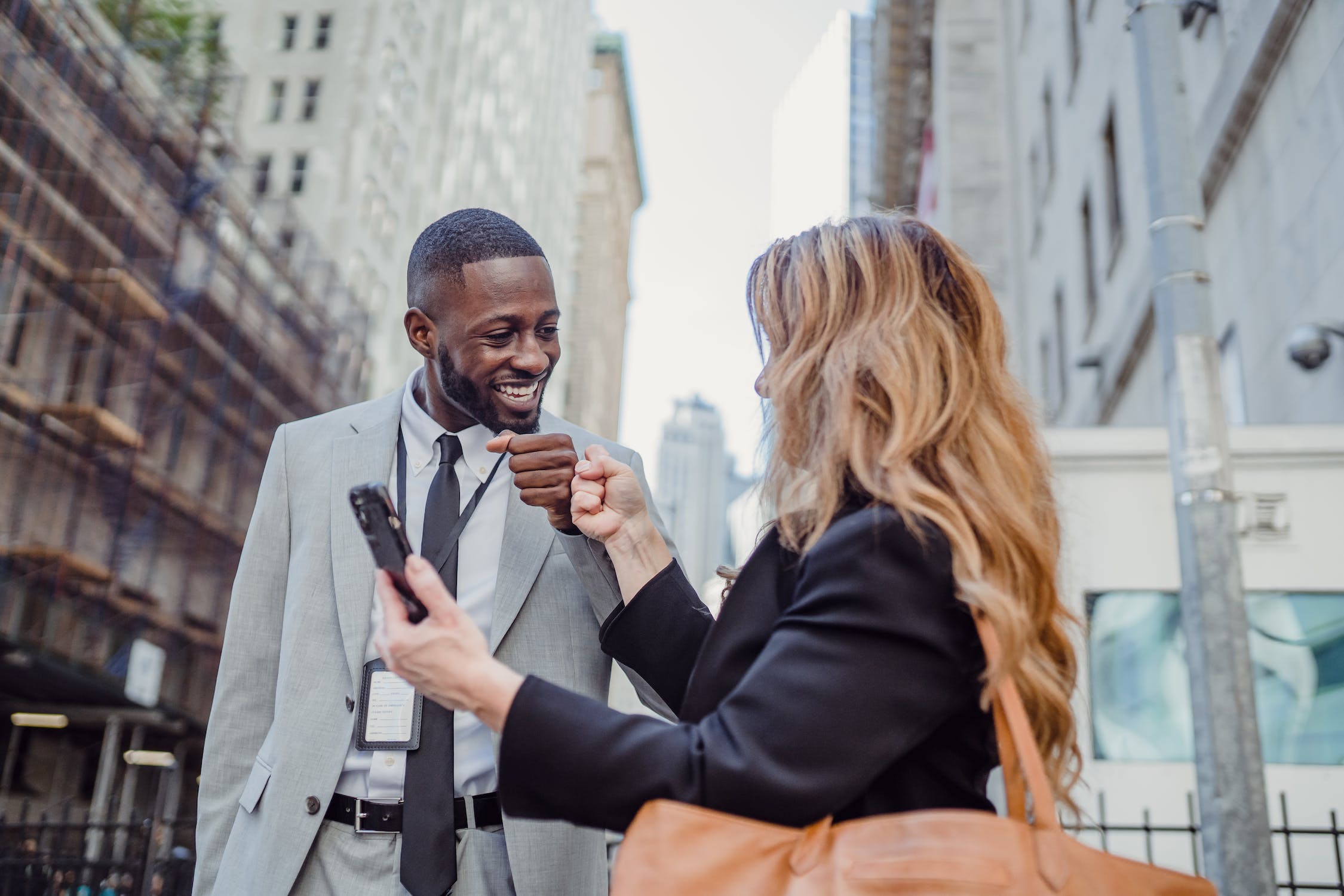 Man and woman fistbumping each other while looking at a phone